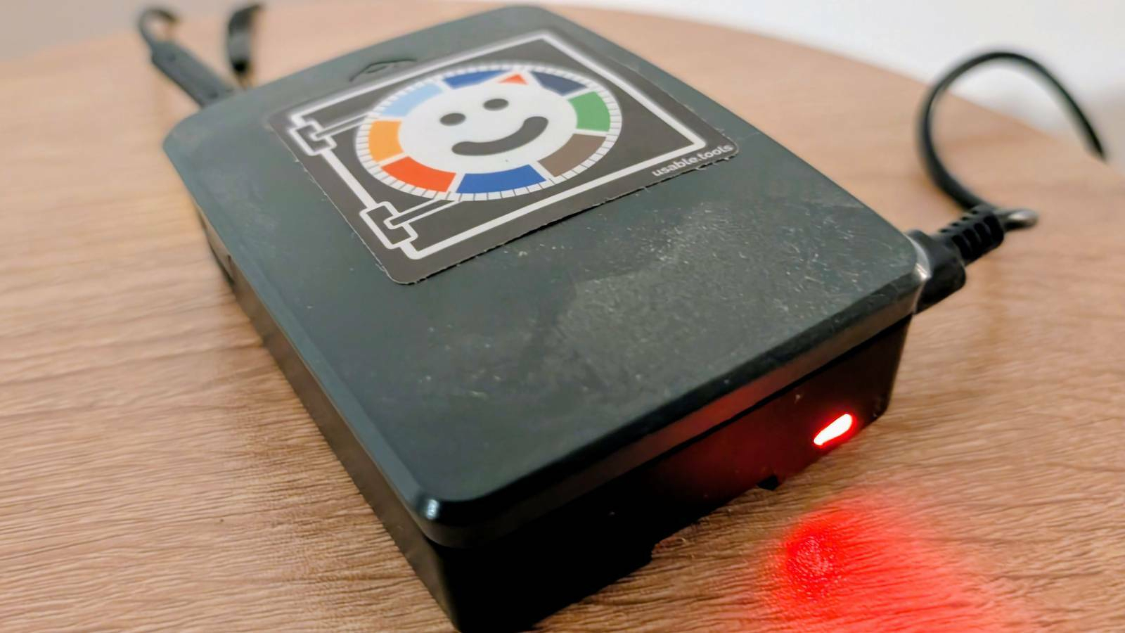 A raspberry pi in a black case that has a happy usable.tools sticker on it.